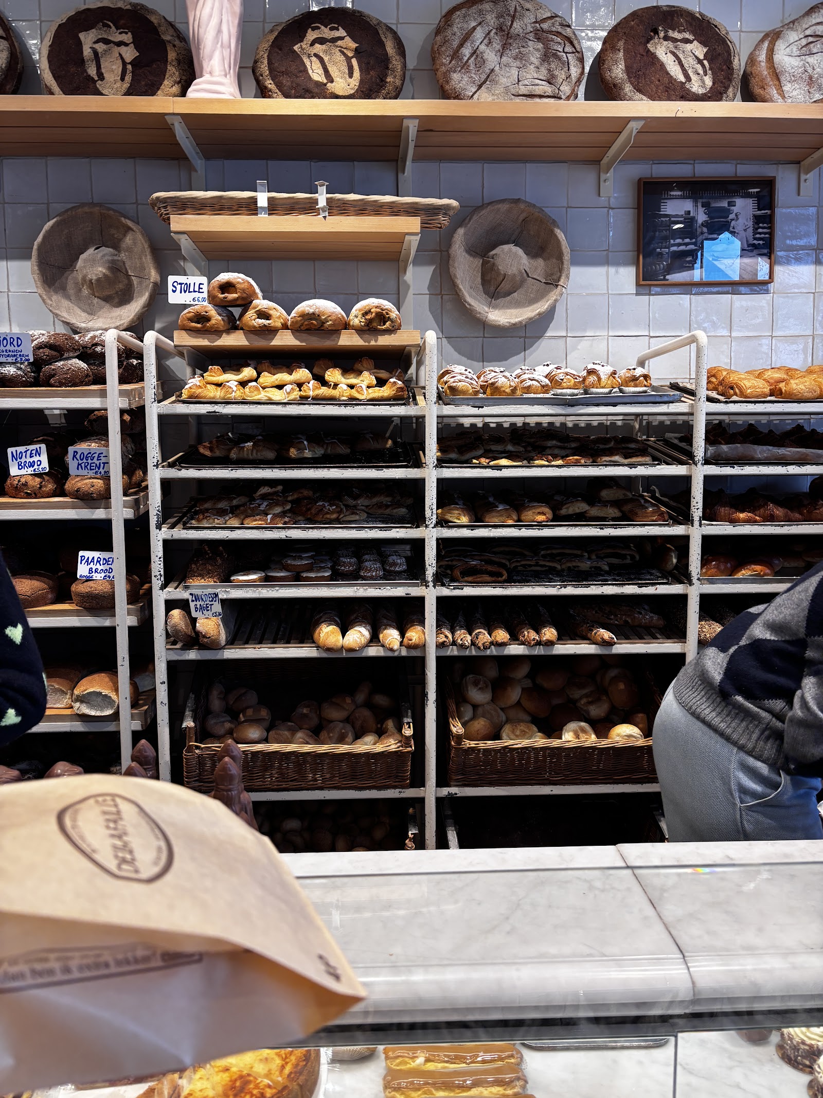 Rekken vol vers brood en grote zuurdesembroden in de winkel van Bakkerij Dellafaille